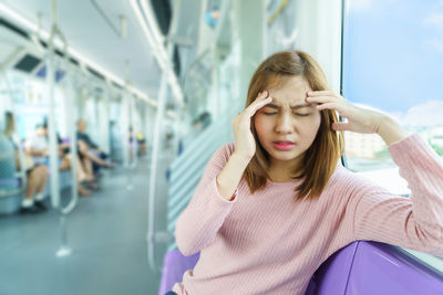 Young woman suffering from headache while traveling in train