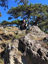 Low angle view of man on rock against trees