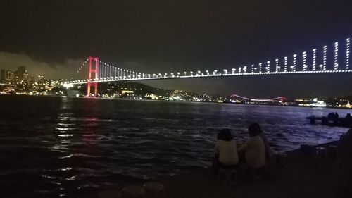 Illuminated suspension bridge over river at night