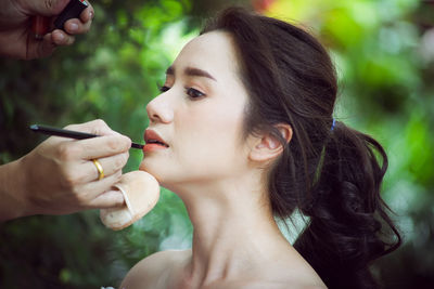 Close-up of person applying make-up on woman face