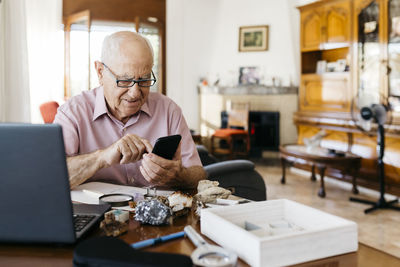 Man using mobile phone while sitting on table