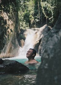 Portrait of young woman by waterfall in forest