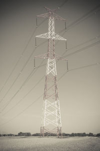 Low angle view of electricity pylon on field