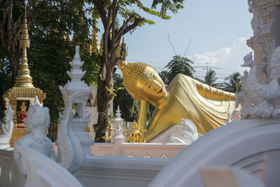 Statue amidst trees and buildings against sky