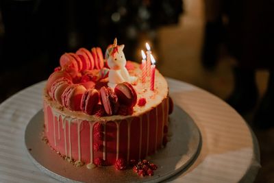 View of anniversary unicorn pink cake with lit candles 