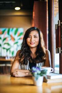 Portrait of smiling young woman sitting on table