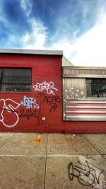 Graffiti on building against cloudy sky