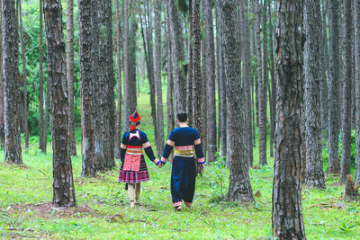 Rear view of people walking in forest