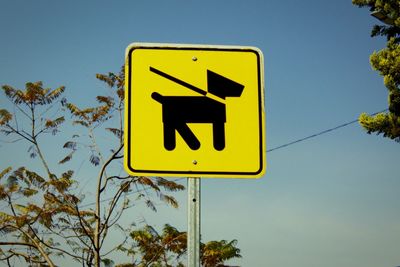 Low angle view of road sign against clear blue sky