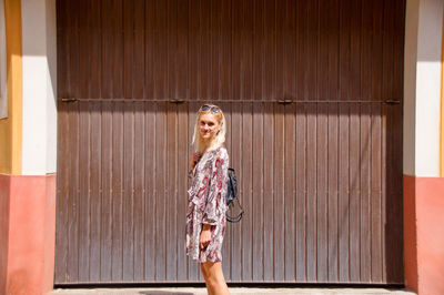 Portrait of a smiling young woman standing against wall