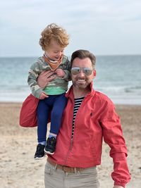 Smiling father and son standing at beach