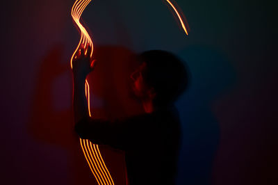 Midsection of man with illuminated light painting at night