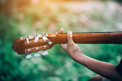 Cropped hand of person playing guitar over field