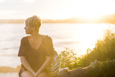 Woman sitting on trunktree on sunset