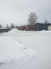 Snow covered field by buildings against sky