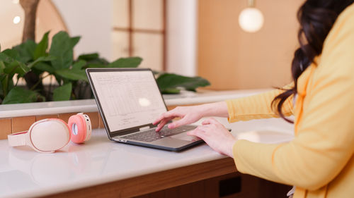 Midsection of woman using laptop on table