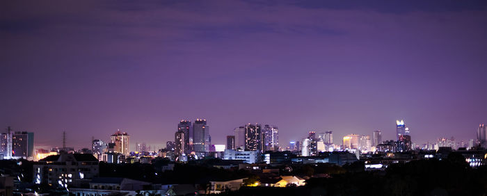 Illuminated buildings in city against sky at night