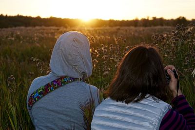 Rear view of couple photographing on field