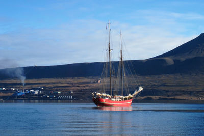 Sailboats moored in sea against sky