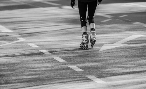 Low section of woman roller skating on road