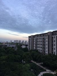 Trees and cityscape against sky during sunset