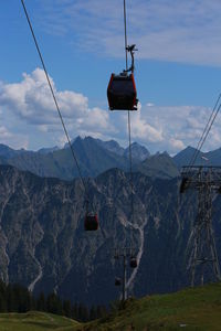 Overhead cable cars over mountains against sky