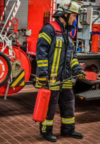 Full length of firefighter holding cylinder