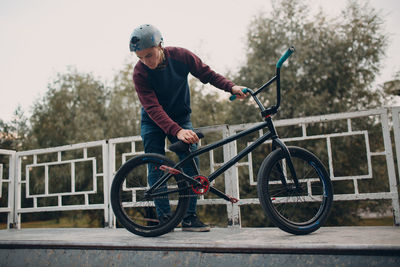 Man with bicycle by railing outdoors