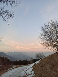 Snow covered landscape against sky during sunset