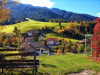 Scenic view of trees and houses on field by mountains