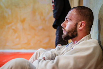 Young man looking away while sitting on floor