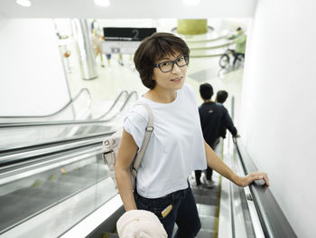 Side view of young woman sitting on escalator
