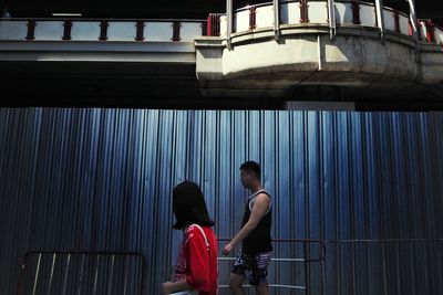 Rear view of two people standing against building