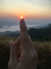 Midsection of person against sky during sunset