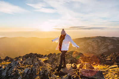 Man standing on rock against sky during sunset