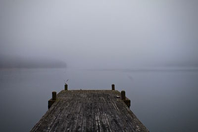 Empty pier over lake against sky