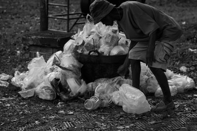 Full length of homeless man standing by garbage pile