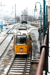 Train on railroad track in city against sky during winter