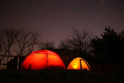 Illuminated tents on field against sky at night