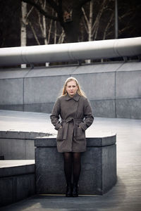 Young woman standing against wall