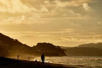 Silhouette man on beach against sky during sunrise