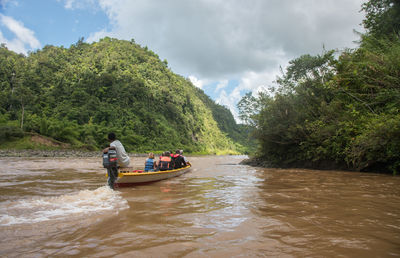 People in boat on river against sky