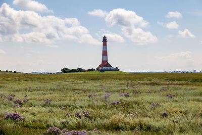 Lighthouse on field against sky