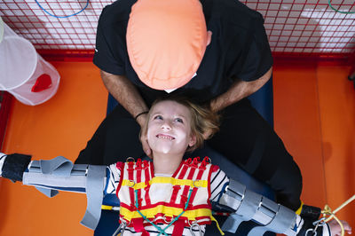 Crop anonymous specialist giving support to girl with angelman syndrome during rehabilitation training with elastic straps