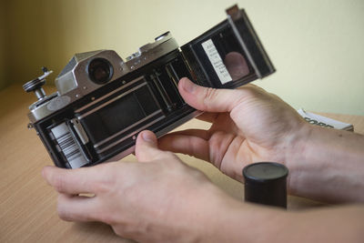 Cropped image of hand holding old-fashioned camera at table