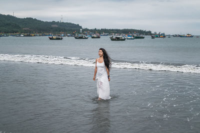 Woman standing on beach against sky