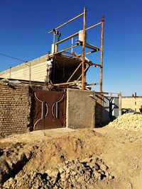 Low angle view of abandoned building against clear blue sky