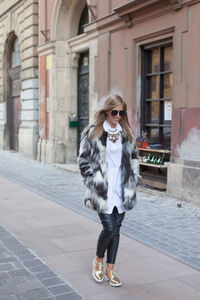 Portrait of young woman walking on street in city