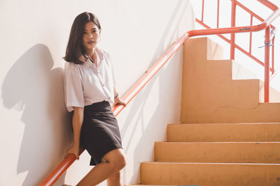 Portrait of woman on staircase against wall