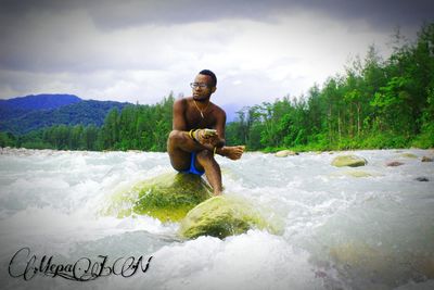 Portrait of shirtless man in water against sky